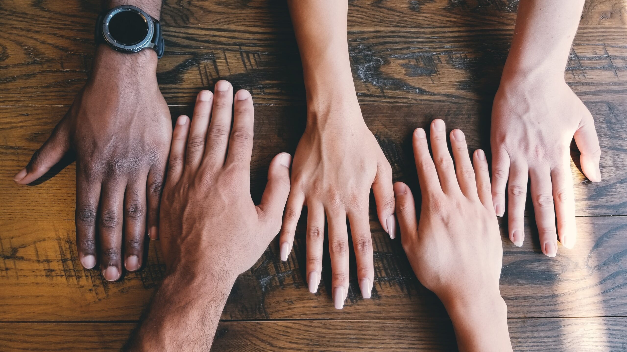 5 hands on wooden table